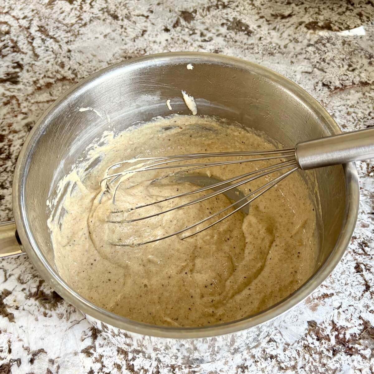 Chia cheese in a steel pot with a whisk.
