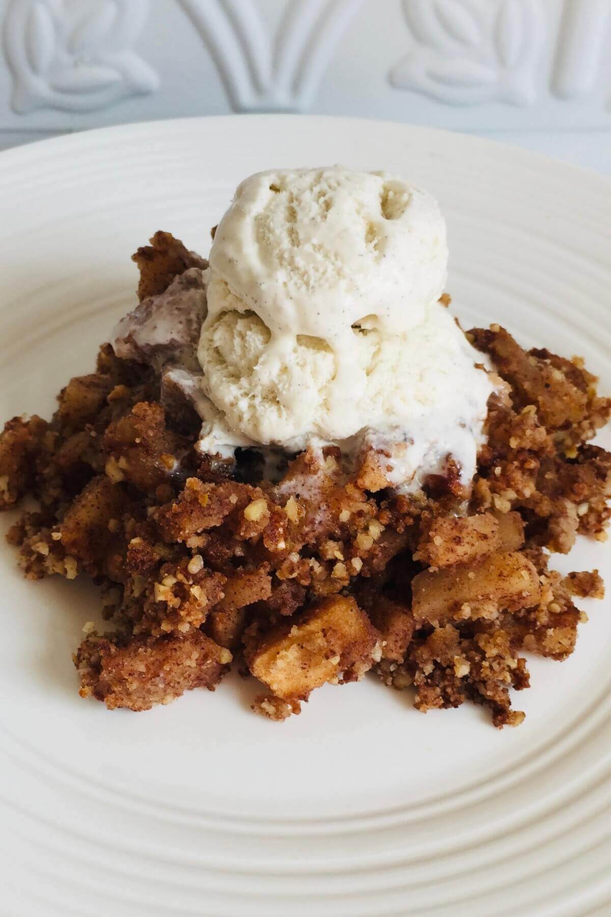 A serving of coconut flour apple crisp on a white plate.