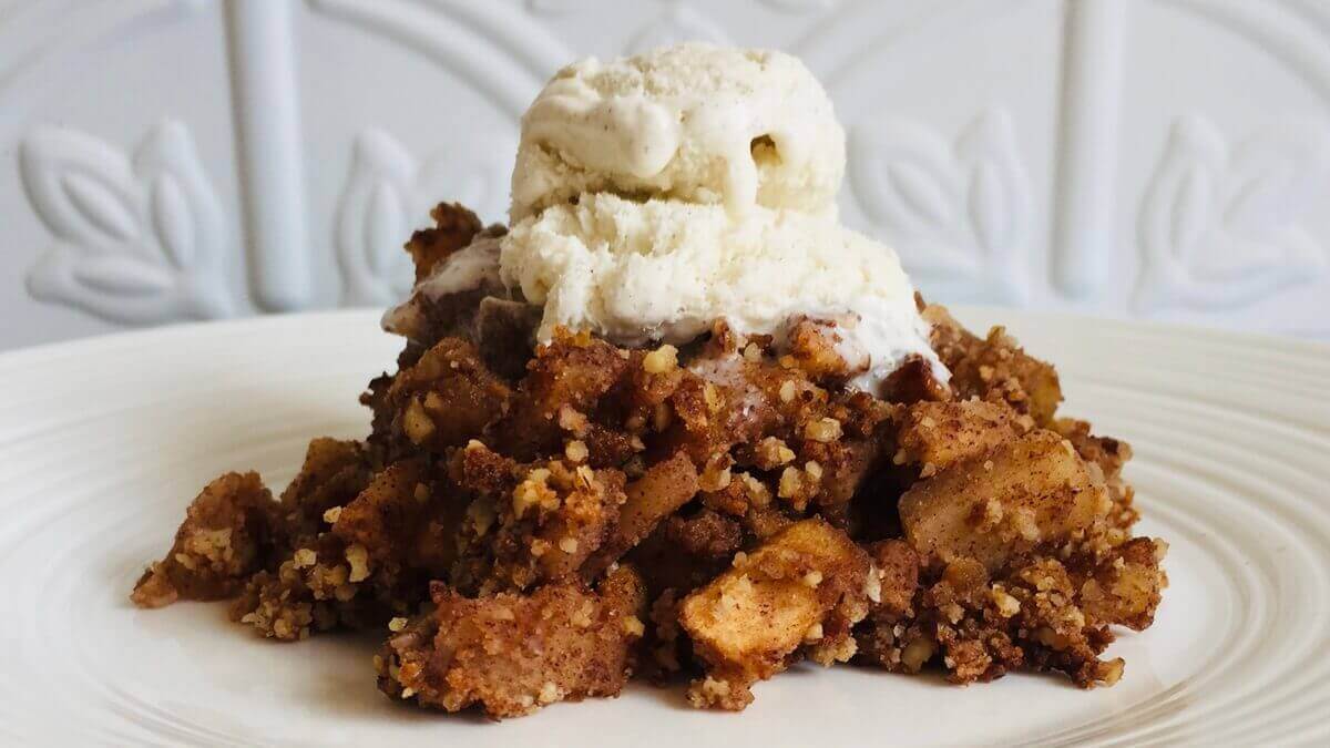 Coconut flour apple crumble with a scoop of ice cream melting on top.