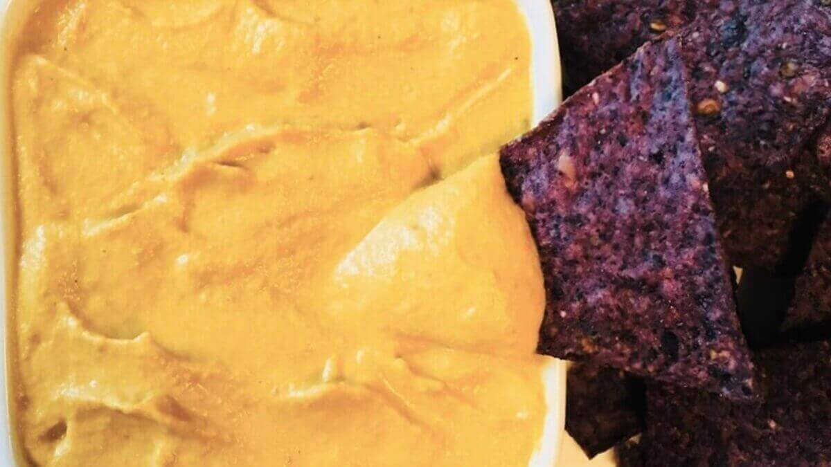 Vegan pumpkin queso and blue corn chips.