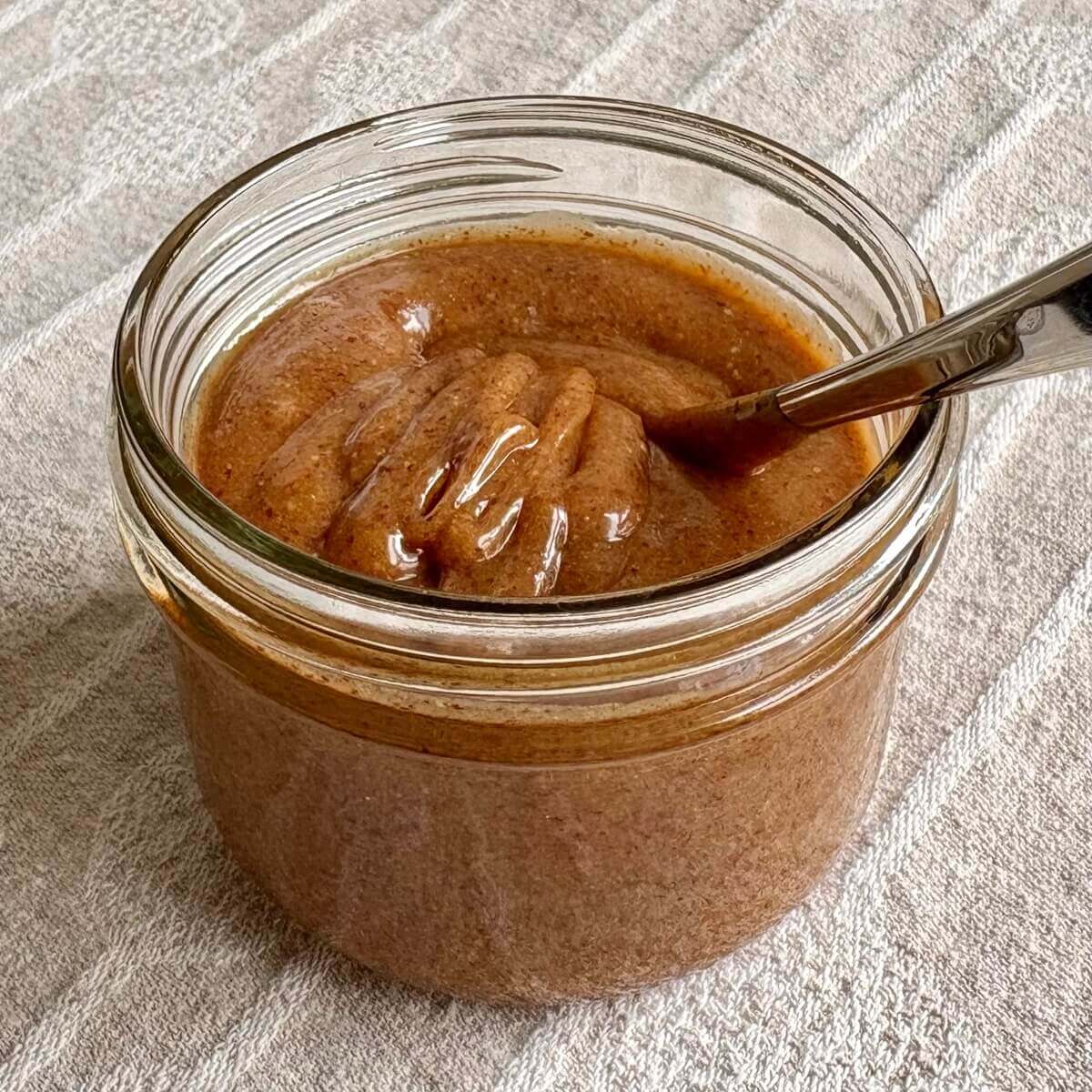 Almond butter caramel sauce in a jar with a spoon.