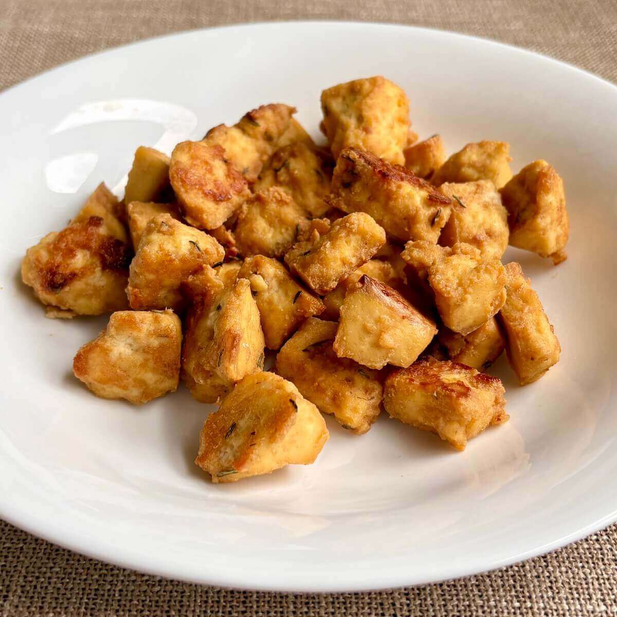 Bite-sized pieces of maple mustard tofu in a white bowl.