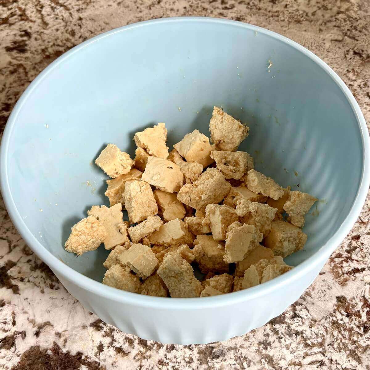 Tofu marinating in a blue bowl.
