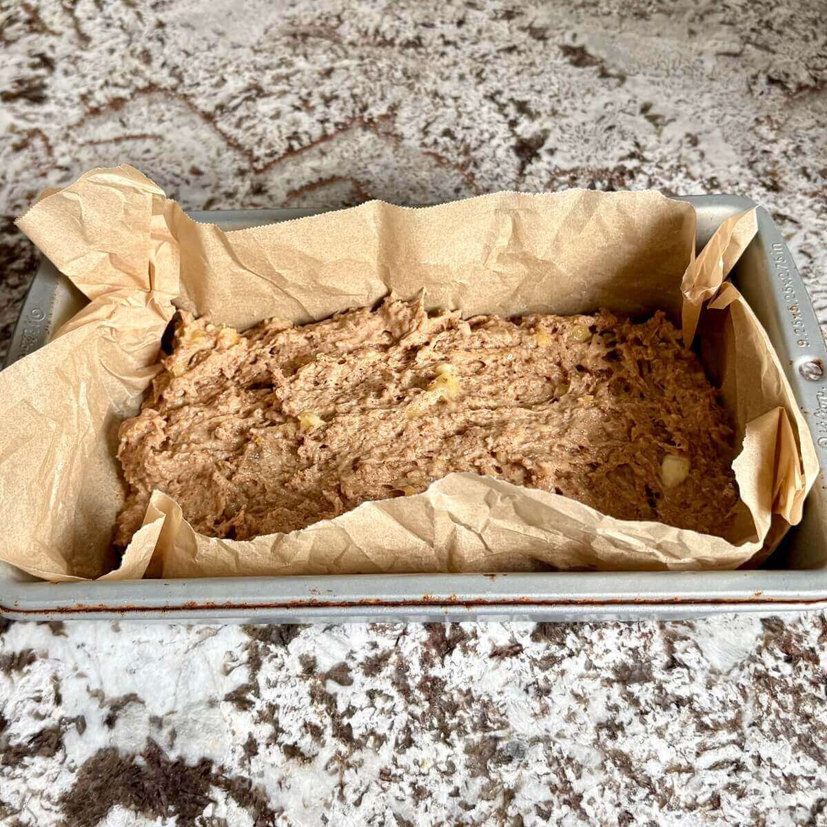 No-sugar banana bread batter in a loaf pan lined with parchment paper.