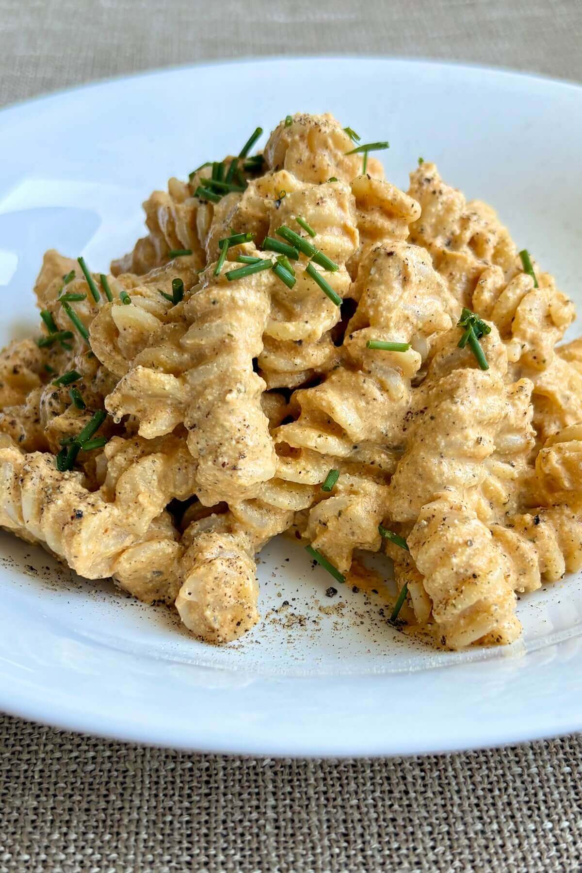 Pasta with a vegan pumpkin sauce in a white bowl.