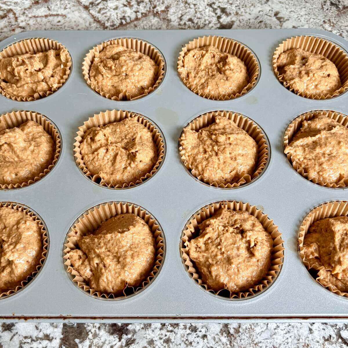 Raw pumpkin muffins in a muffin pan.