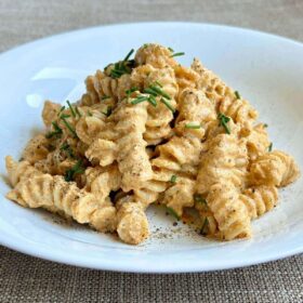 Noodles tossed with vegan pumpkin pasta sauce and sprinkled with chives.