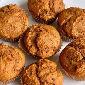 Seven vegan pumpkin spice muffins on a white plate.