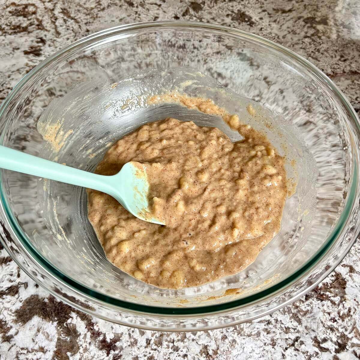Wet ingredients for banana bread in a glass mixing bowl.