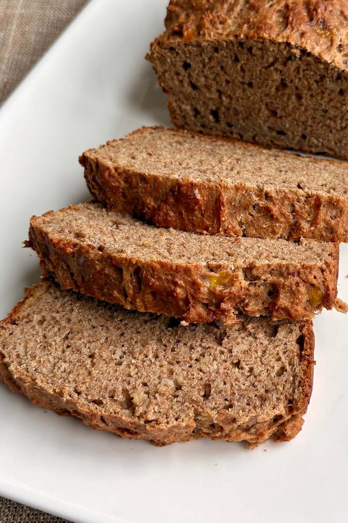 Slices of vegan whole wheat banana bread on a white plate.